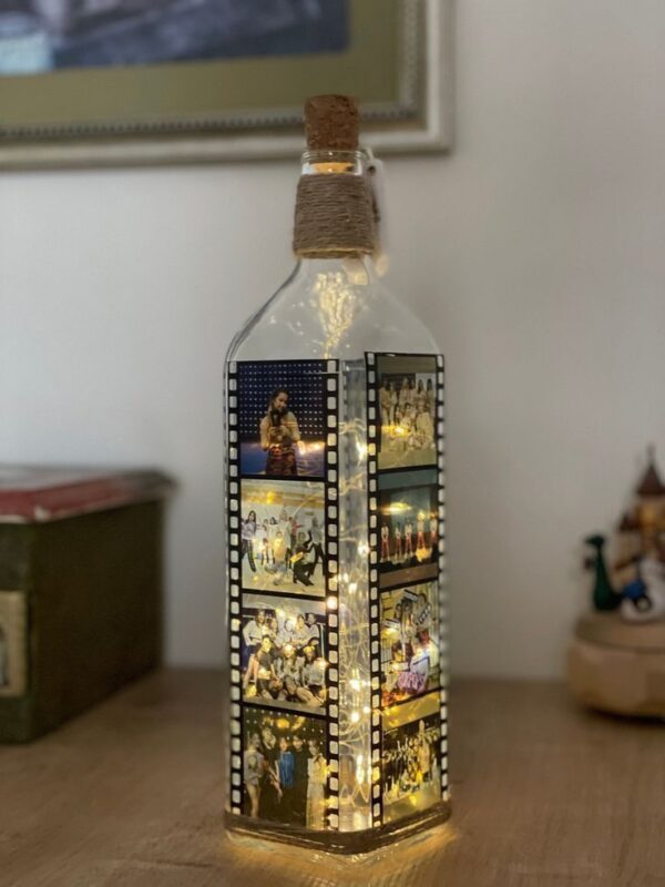 Customized glass bottle lamp with a filmstrip-style photo collage and LED fairy lights, perfect for personalized gifting and home décor.